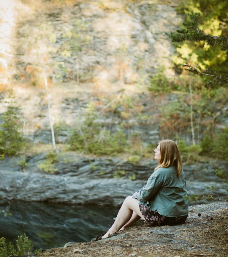 Frau in der Natur sitzend, ins Weite schauend