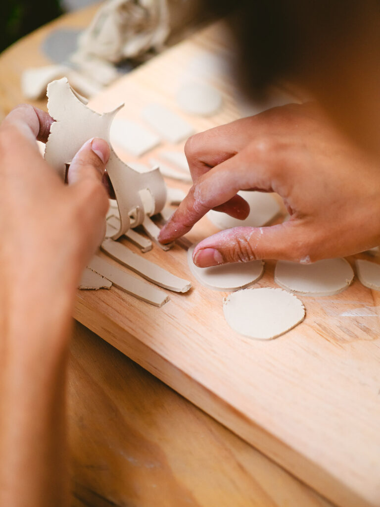 Hände formen Ton auf Holzbrett