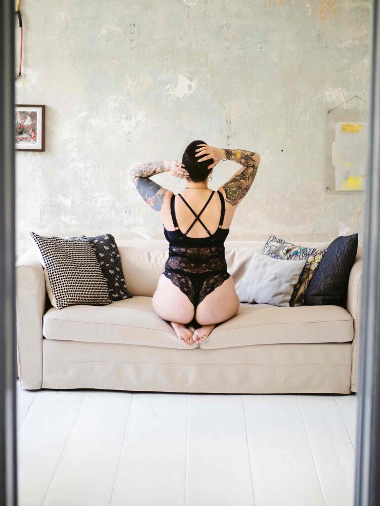 Boudoir Shooting Location Berlin – privates Studio mit Sofa, Tattoos und rohen Wänden.