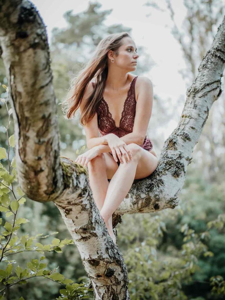 Frau sitzt auf einem Baum im Abendlicht