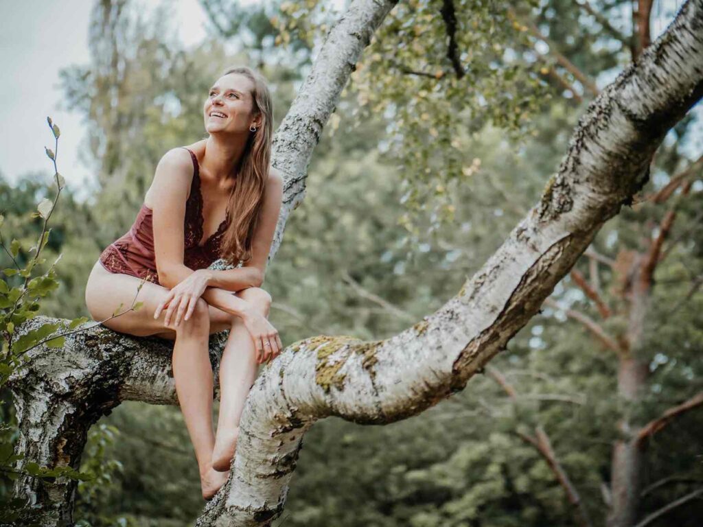 Boudoir Shooting Location Berlin Outdoor – Frau sitzt auf einem Baum im Abendlicht
