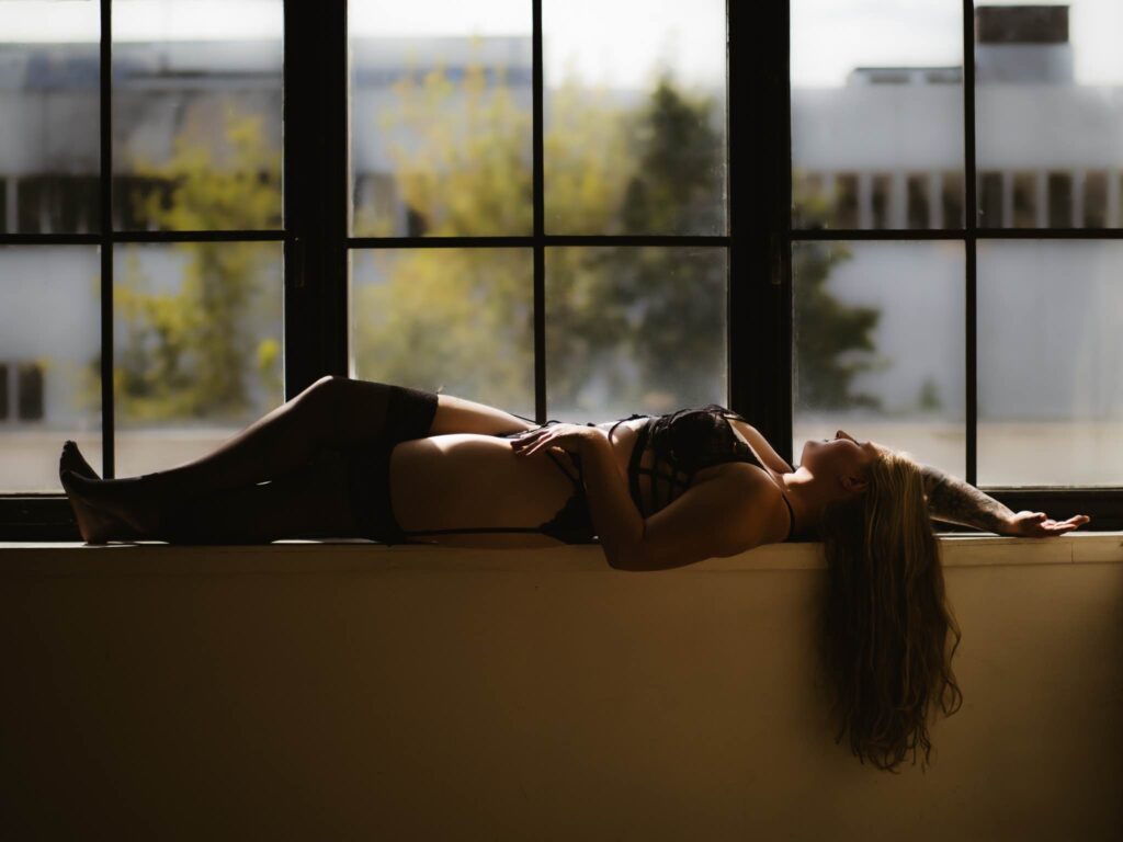 Frau liegt in einem klassischen Fotostudio auf der Fensterbank